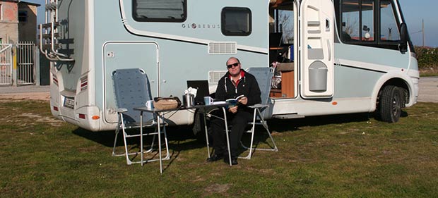 Peter Budig sitzt in Sonne vor Camper